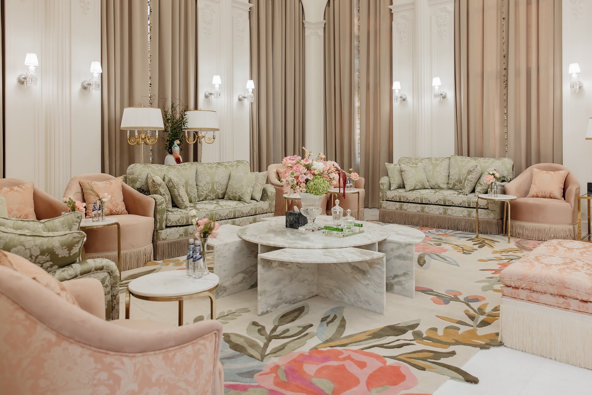 Real project seating area with marble table, sage sofas, blush chairs, brass lamps, and warm taupe curtains